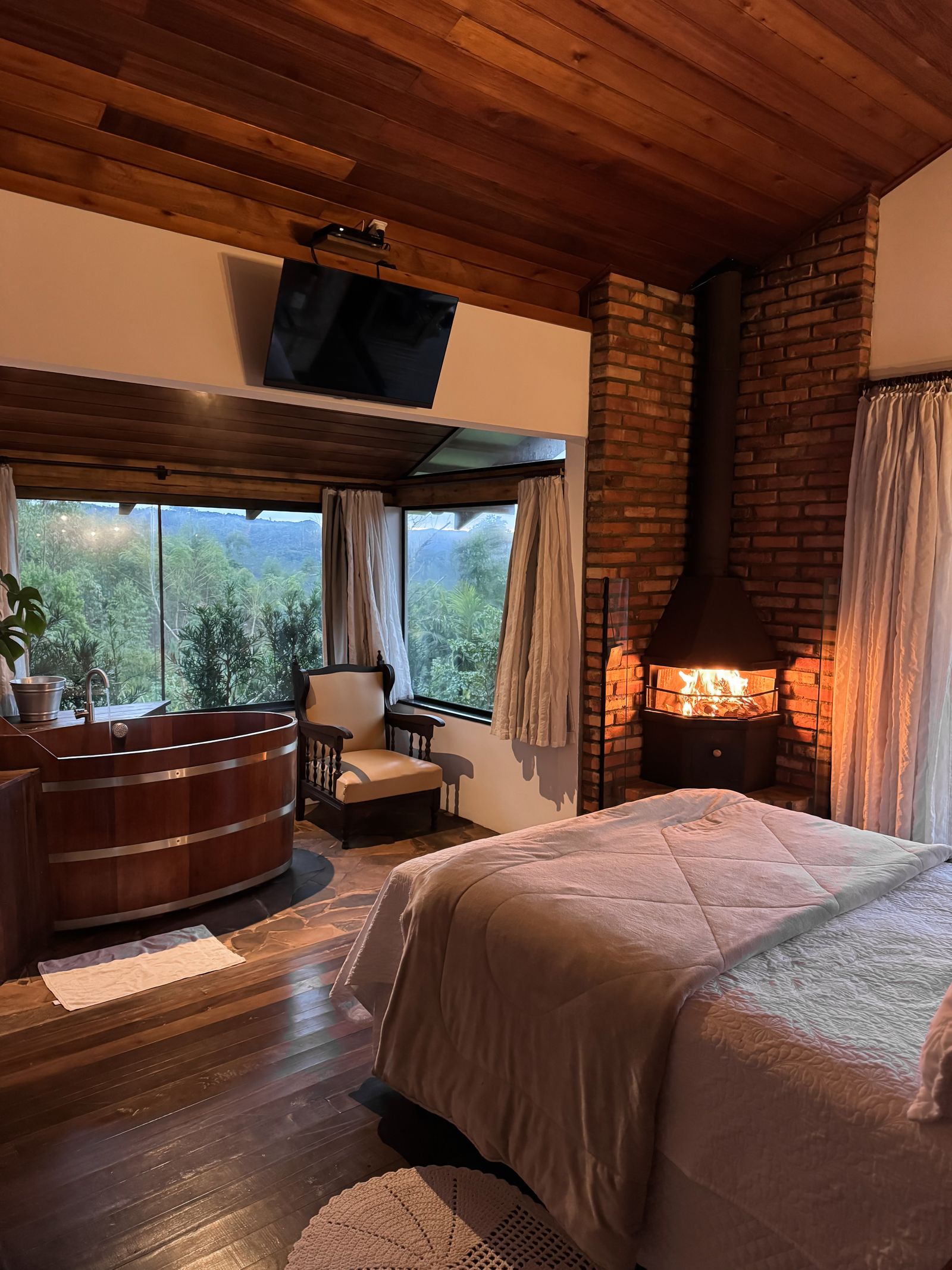 Quarto com lareira acesa e janela para o vale